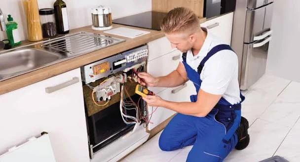 Technician checking the exposed components of a kitchen dishwasher