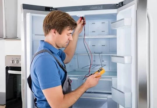 Technician diagnosing a refrigerator with a handheld multimeter